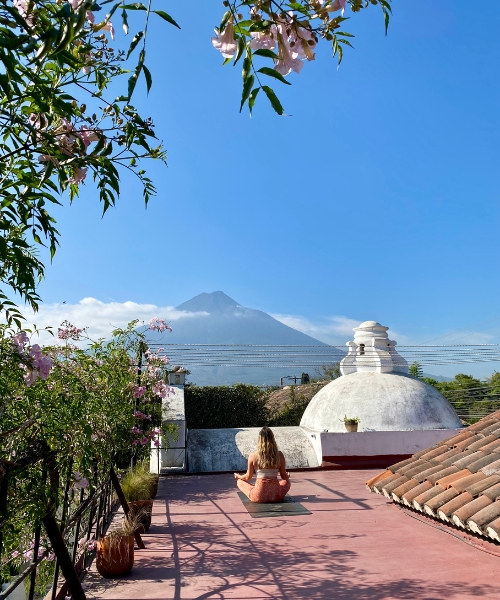 femme en train de faire du yoga sur un rooftop face à un volcan au guatemala