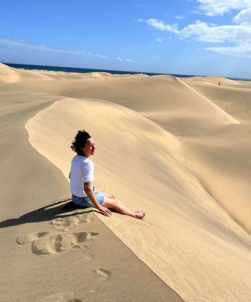 femme assise en haut d'une dune de sable sur une île des canaries